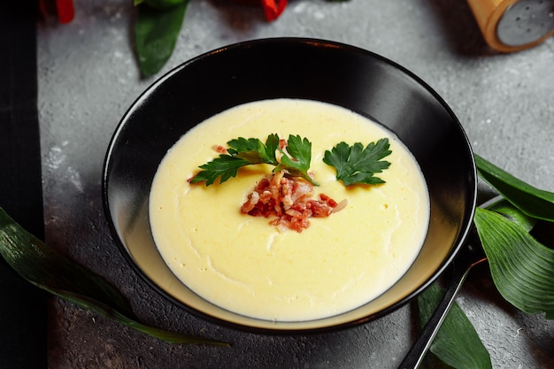 Tazón de fuente de sopa de crema de queso sabroso con tocino en gris