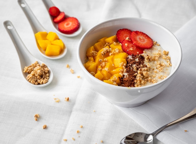 Tazón de gachas de avena con mango de fresas y nueces picadas