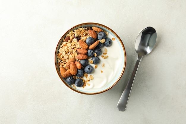 Tazón de granola y cuchara sobre fondo blanco.