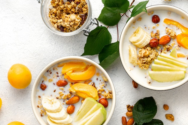 Tazón de granola con frutas, nueces, leche y mantequilla de maní en un tazón. Vista superior de cereales para el desayuno saludable