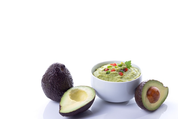 Tazón de guacamole con aguacates aislado sobre fondo blanco con espacio de copia.