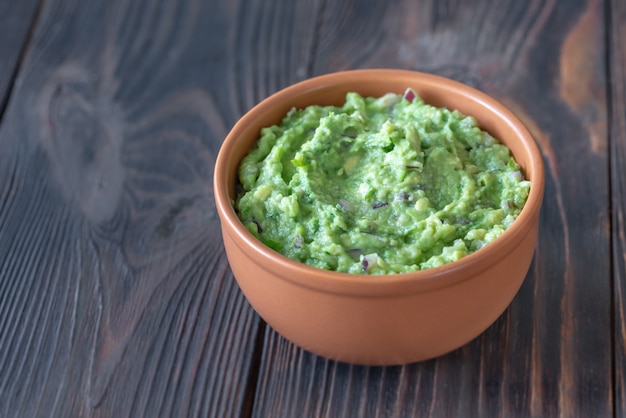 Tazón de guacamole en la mesa de madera