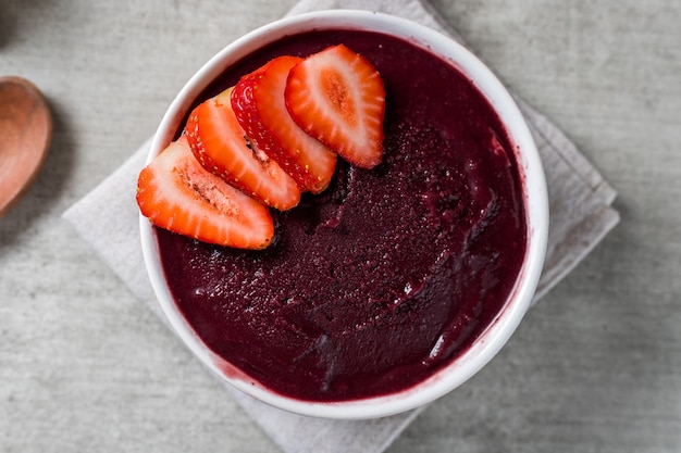 Tazón de helado brasileño congelado y de acai berry con fresas. con frutas sobre fondo de madera. Vista superior del menú de verano. de cerca.