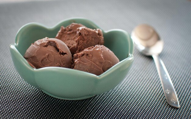 un tazón de helado de chocolate con una cuchara a su lado