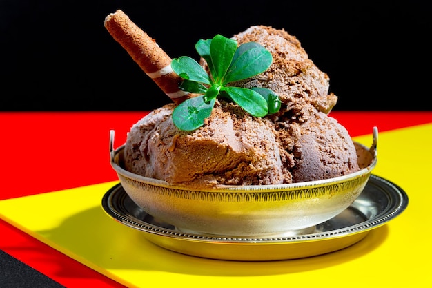 Un tazón de helado de chocolate con una hoja encima.