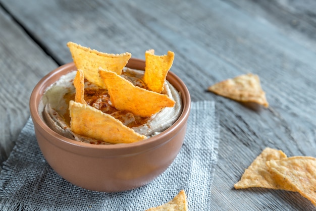 Un tazón de hummus con chips de maíz.