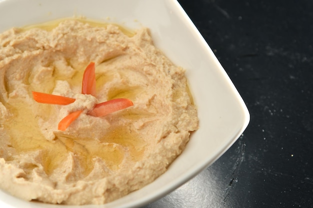 Un tazón de hummus con una rodaja de aceite de oliva.