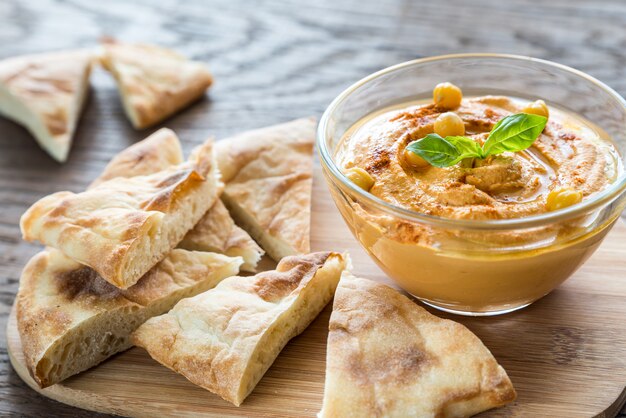 Un tazón de hummus con rodajas de pita