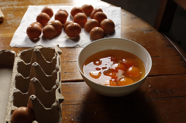 Un tazón de jugo de naranja se encuentra en una mesa junto a una docena de huevos.