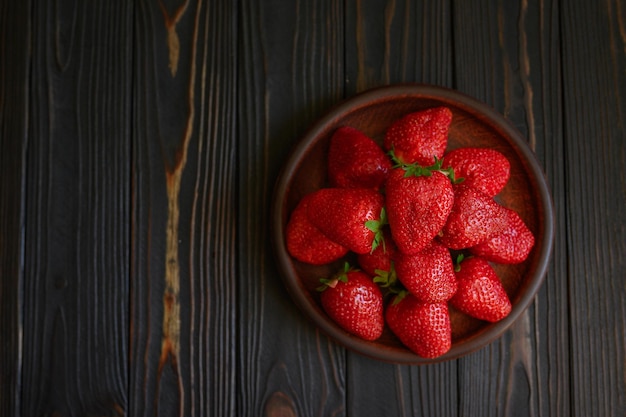 Un tazón de jugosas fresas rojas sobre una mesa de madera rústica Concepto de bocadillos saludables y dietéticos