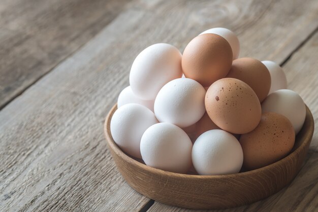 Tazón de madera de huevos de gallina cruda