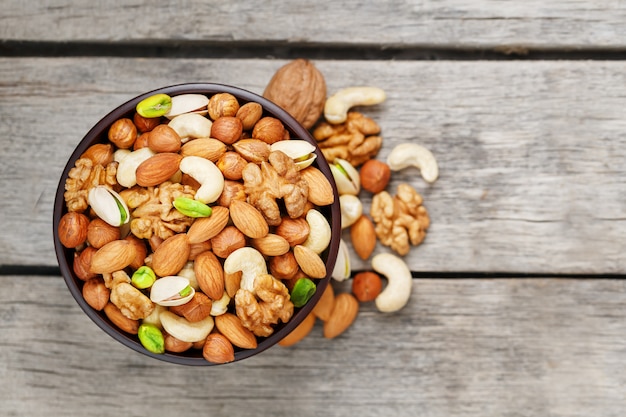 Tazón de madera con nueces mixtas sobre una superficie de madera gris