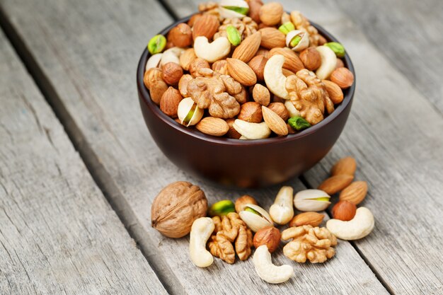 Tazón de madera con nueces mixtas sobre una superficie de madera gris