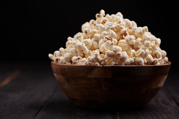 Tazón de madera con palomitas de maíz saladas en una mesa de madera