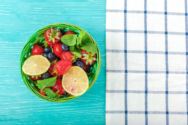 Tazón en mesa de madera, fresas y arándanos dentro