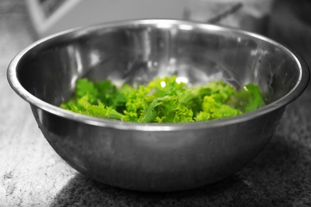 Tazón de metal con lechuga verde en la mesa vista de cerca