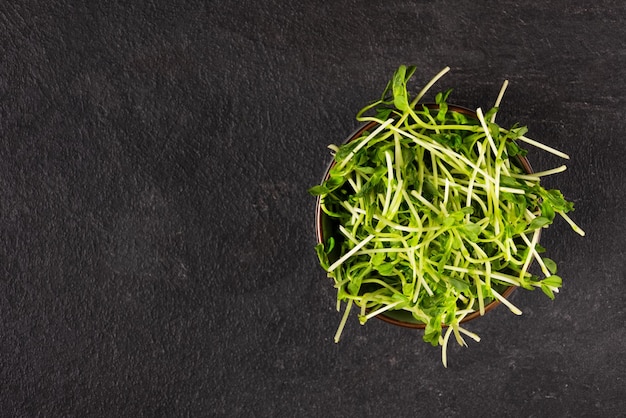 Tazón con microgreens de guisantes sobre fondo negro vista superior Semillas germinadas Brotes de alimentación saludable