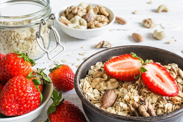 Tazón de muesli de avena con fresa, granola y nueces sobre mesa de madera rústica