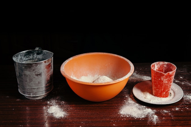 Tazón de naranja y harina en la mesa de la cocina de cerca