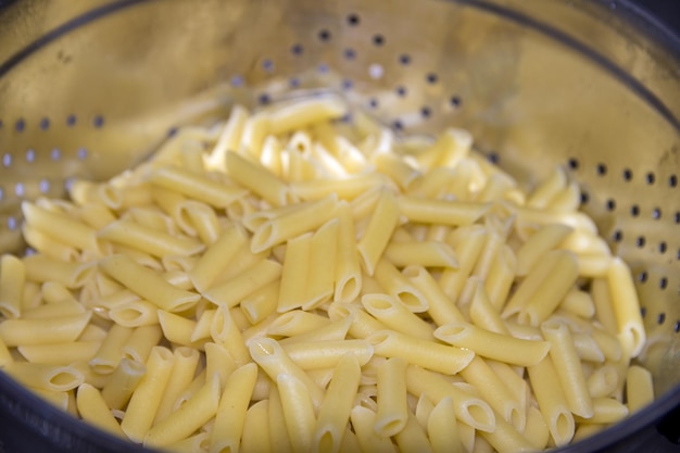 Un tazón de pasta con un colador de metal que dice "pasta"