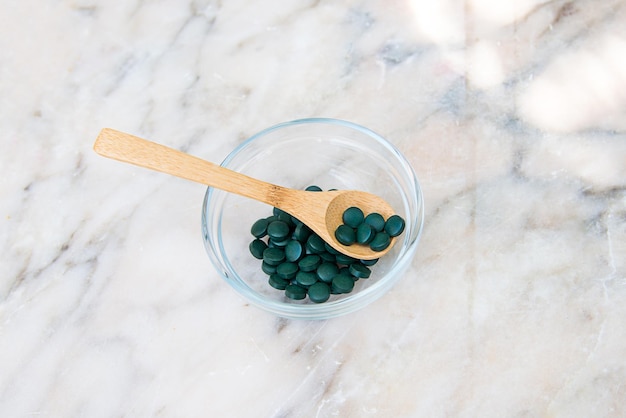 Un tazón de pastillas verdes sobre una encimera de mármol.