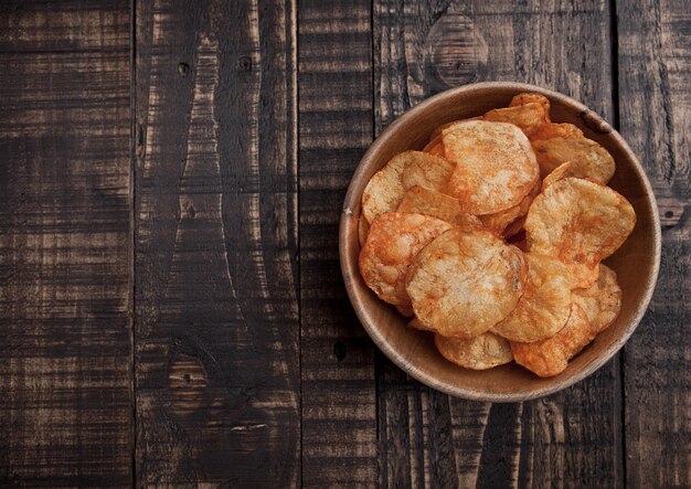 Tazón con patatas fritas fritas en tablero de madera