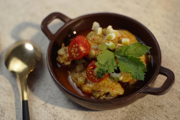 Un tazón de pollo al curry con rodajas de tomate y apio encima