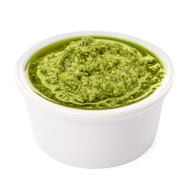 Tazón de sabrosa salsa pesto aislado en blanco