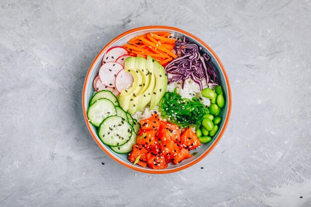 Tazón de salmón con arroz, aguacate, algas, zanahorias en escabeche, pepino, rábanos y frijoles edamame.