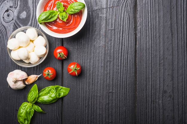 Tazón de salsa de tomate y mozzarella con albahaca y ajo en mesa de madera