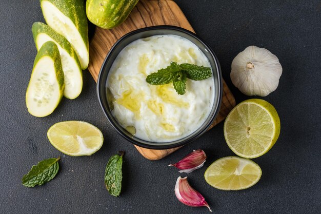 Un tazón de salsa de tzatziki y palitos de verduras cortadas frescas a su lado