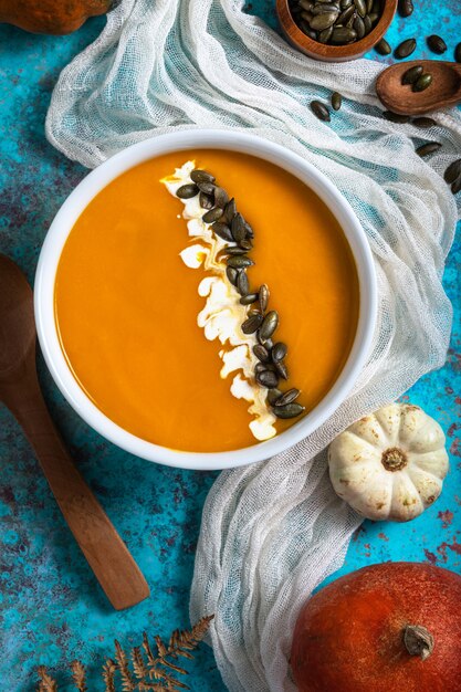 Tazón de sopa de calabaza blanca sobre fondo azul.