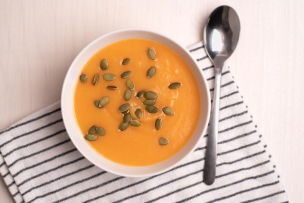 Un tazón de sopa de calabaza con una cuchara sobre un fondo claro Comida saludable Comida vegana Vista superior plana