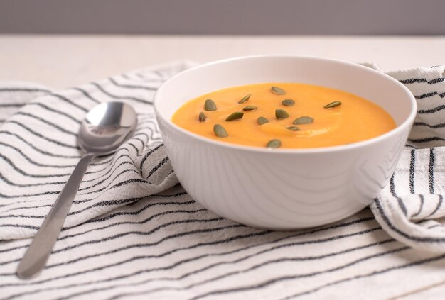 Un tazón de sopa de calabaza con una cuchara sobre un fondo claro Comida saludable comida vegana