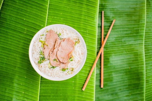 Tazón de sopa de carne de vacuno tradicional vietnamita Pho Bo sobre fondo de hoja de plátano