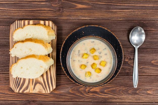 Un tazón de sopa casera de puré de champiñones con pan sobre una mesa de madera Sopa vegetariana casera de champiñones con verduras y pan Vista desde arriba