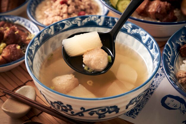 Un tazón de sopa con una cuchara que tiene una albóndiga.