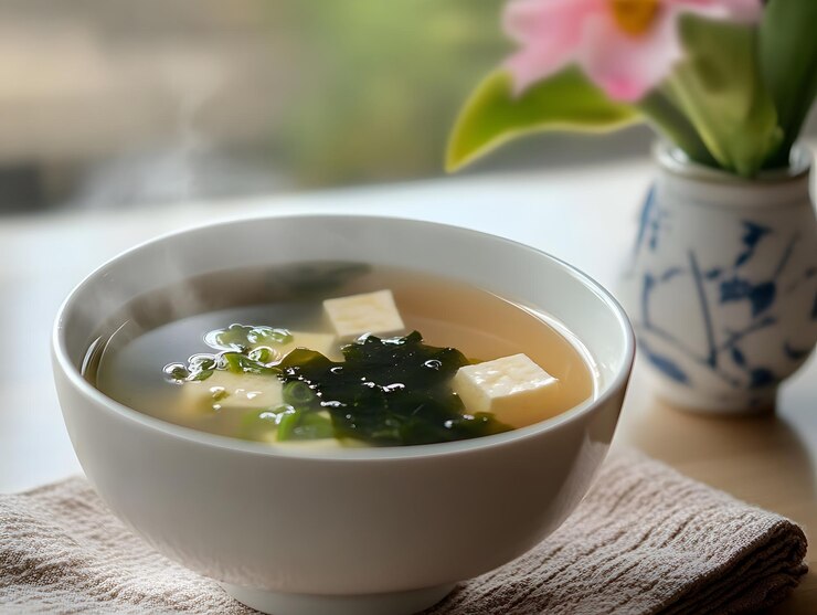 un tazón de sopa con una flor en el fondo y una flor en la parte posterior