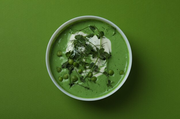 Tazón de sopa de guisantes sobre superficie verde