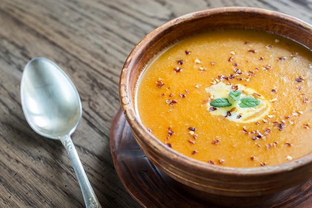 Tazón de sopa picante de crema de calabaza en la mesa de madera