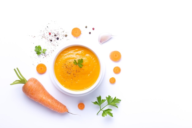 Tazón de sopa de zanahoria con zanahoria aislado sobre fondo blanco.