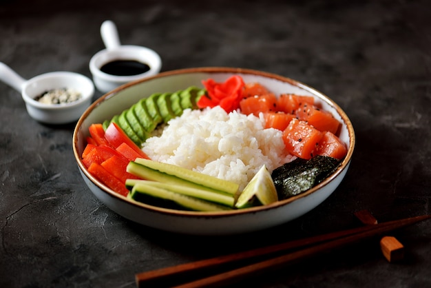 Tazón de sushi con arroz, salmón, aguacate, pepino y sésamo