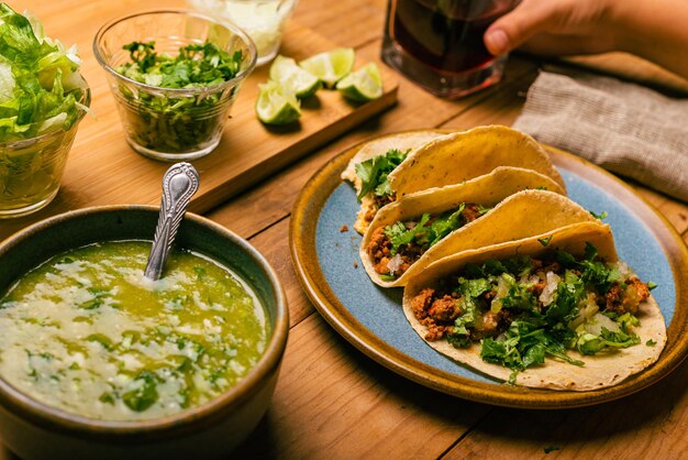 Tazón de tacos de carne marinada con salsa verde y verduras en una mesa de madera Tacos de adobada