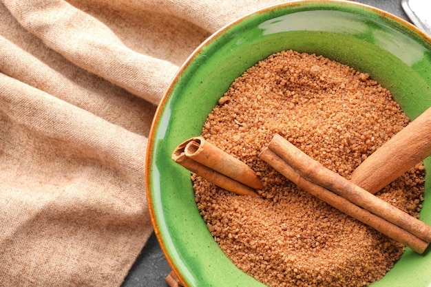 Tazón verde con azúcar de canela y palos en la mesa