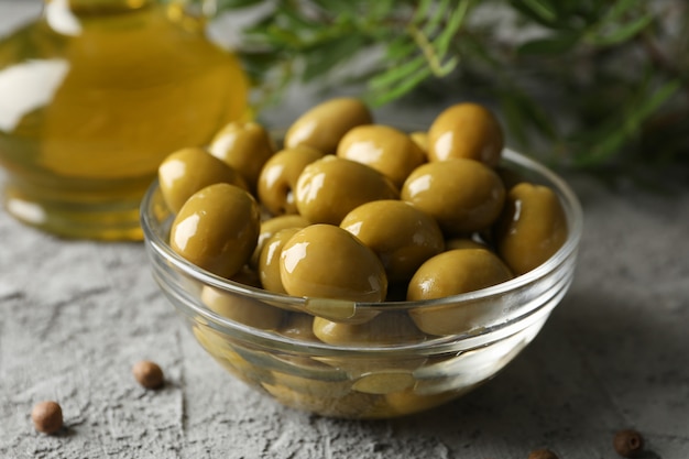 Tazón de vidrio con aceitunas en gris, de cerca