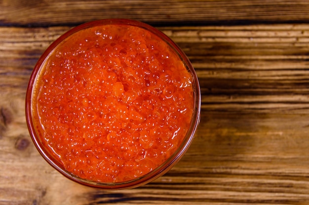 Tazón de vidrio con caviar rojo sobre una mesa de madera Vista superior