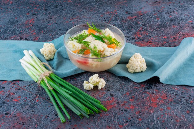 Tazón de vidrio de sopa de verduras orgánicas en la superficie de mármol