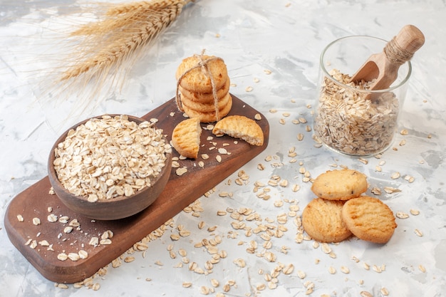 Tazón de vista inferior con galletas de avena atadas con una cuerda sobre un tablero de madera avena en vidrio espigas de trigo en la mesa