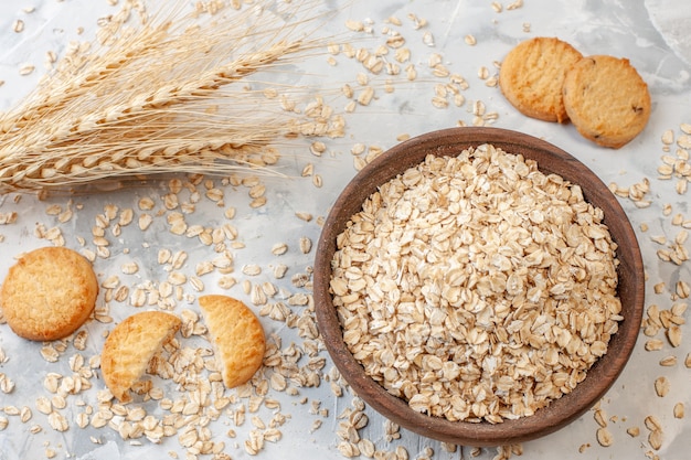 Tazón de vista superior con espigas de trigo avena galletas de avena esparcidas en la mesa