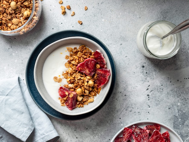 Tazón de yogur griego, granola y naranja sangrienta sobre una superficie gris. concepto de desayuno saludable imagen horizontal, espacio de copia, vista superior de la mesa.